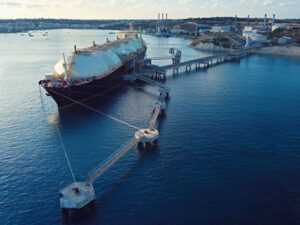 LNG tanker docked at port with loading infrastructure and industrial background.