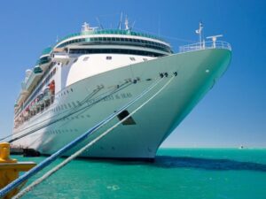 Large luxury cruise ship docked at port with clear blue sky.
