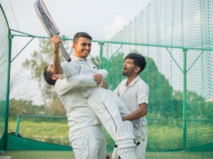 Cricket players celebrating on the field after a match win.