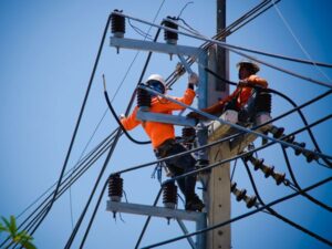 Electric utility workers repairing power lines on a utility pole.