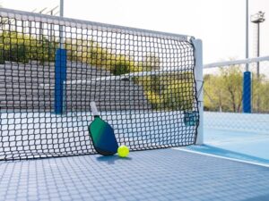 Tennis racket and ball near the net at Cortland sports facility.