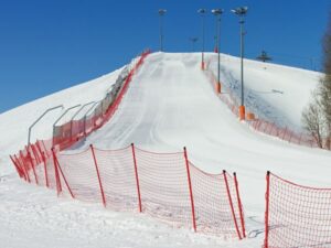 Snow-covered ski jump with safety barriers at Cortland ski resort in winter.